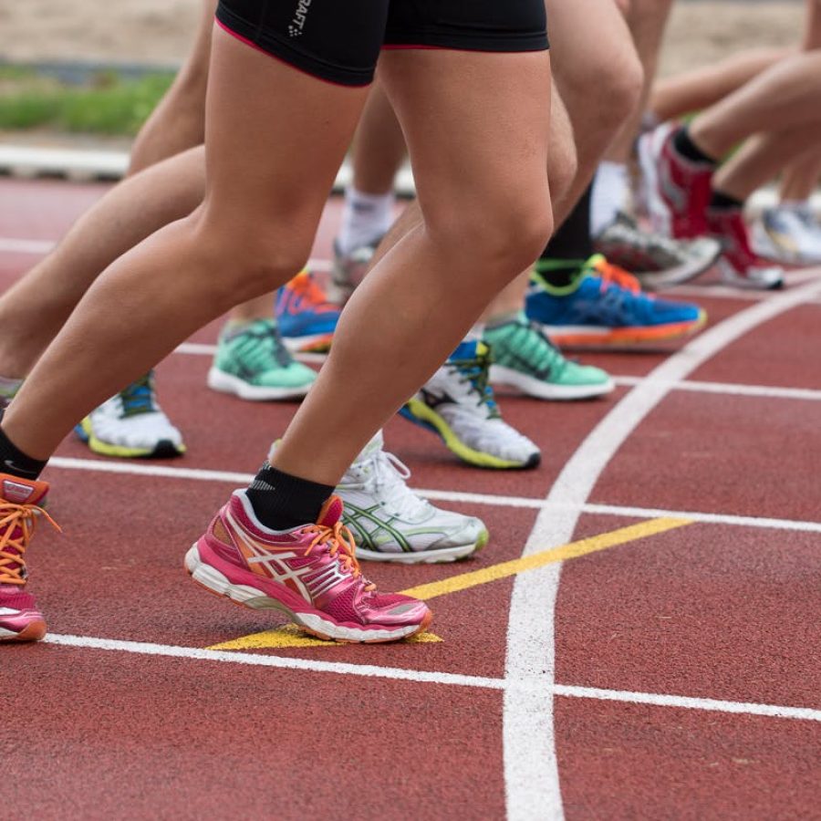Close-up of athletes' feet at the starting line, prepared for a track race.